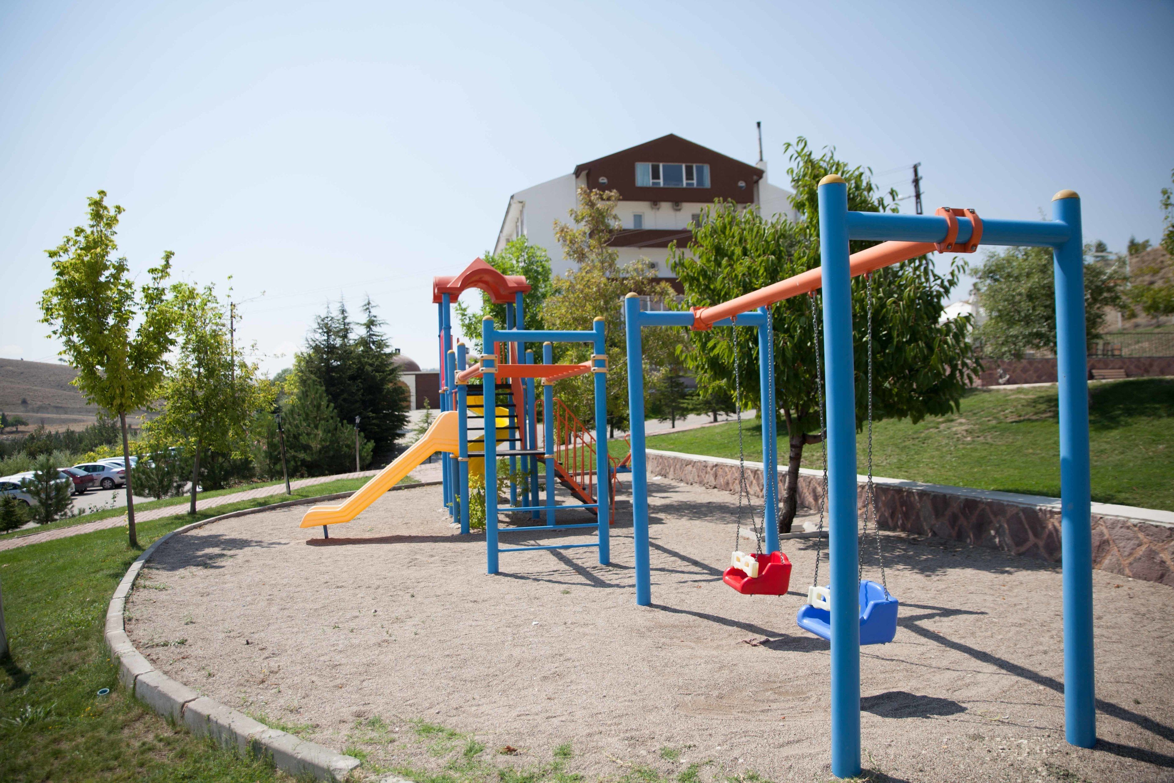 Un parque infantil con tobogán, columpios y estructuras para escalar.
