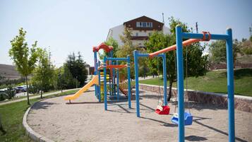 Un parque infantil con tobogán, columpios y estructuras para escalar.