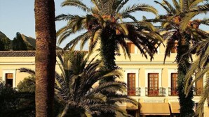Un edificio de fachada amarilla, con varias ventanas y una palmera al frente.