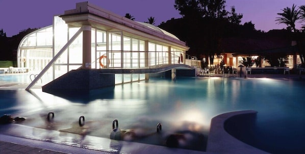 A swimming pool with a glass-enclosed structure, lounge chairs, and a lifebuoy.