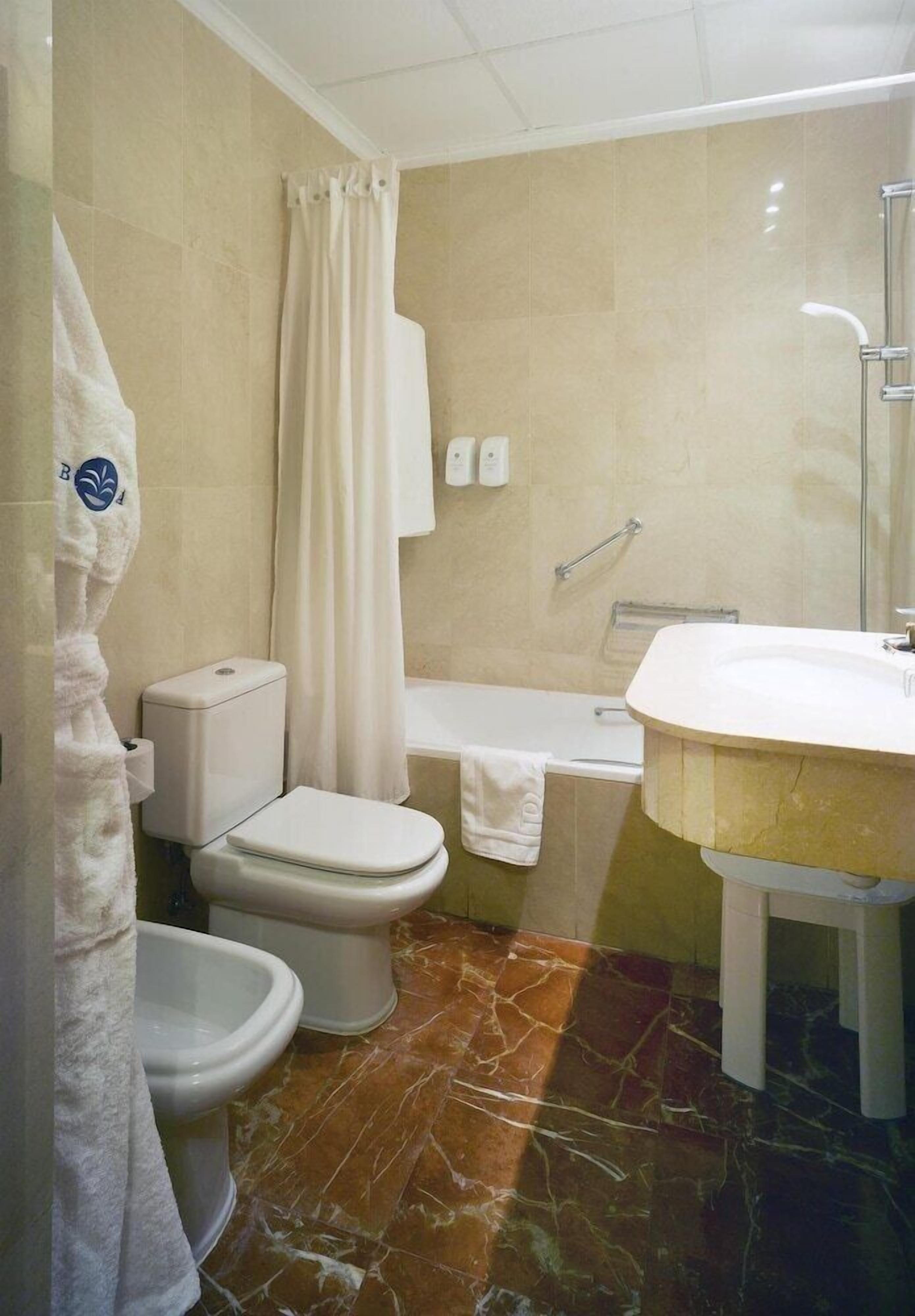 Une salle de bain comprenant des toilettes, un bidet, une baignoire et un lavabo.