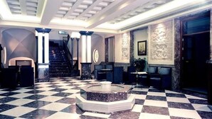 Un vestíbulo con piso de cuadros, una fuente central y una escalera que conduce a niveles superiores.