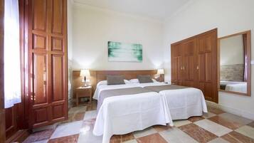 A hotel room with two beds, a large mirror, and a painting on the wall.