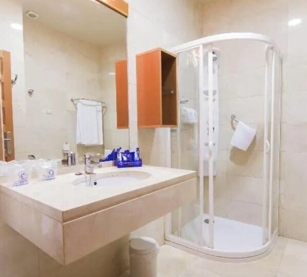 Un baño con lavamanos, espejo y ducha con mampara de vidrio.