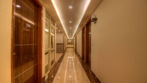 A long, well-lit hallway with a polished floor, wooden doors, and a sign indicating room number 407A. - OPO Viva Palace (New Delhi)