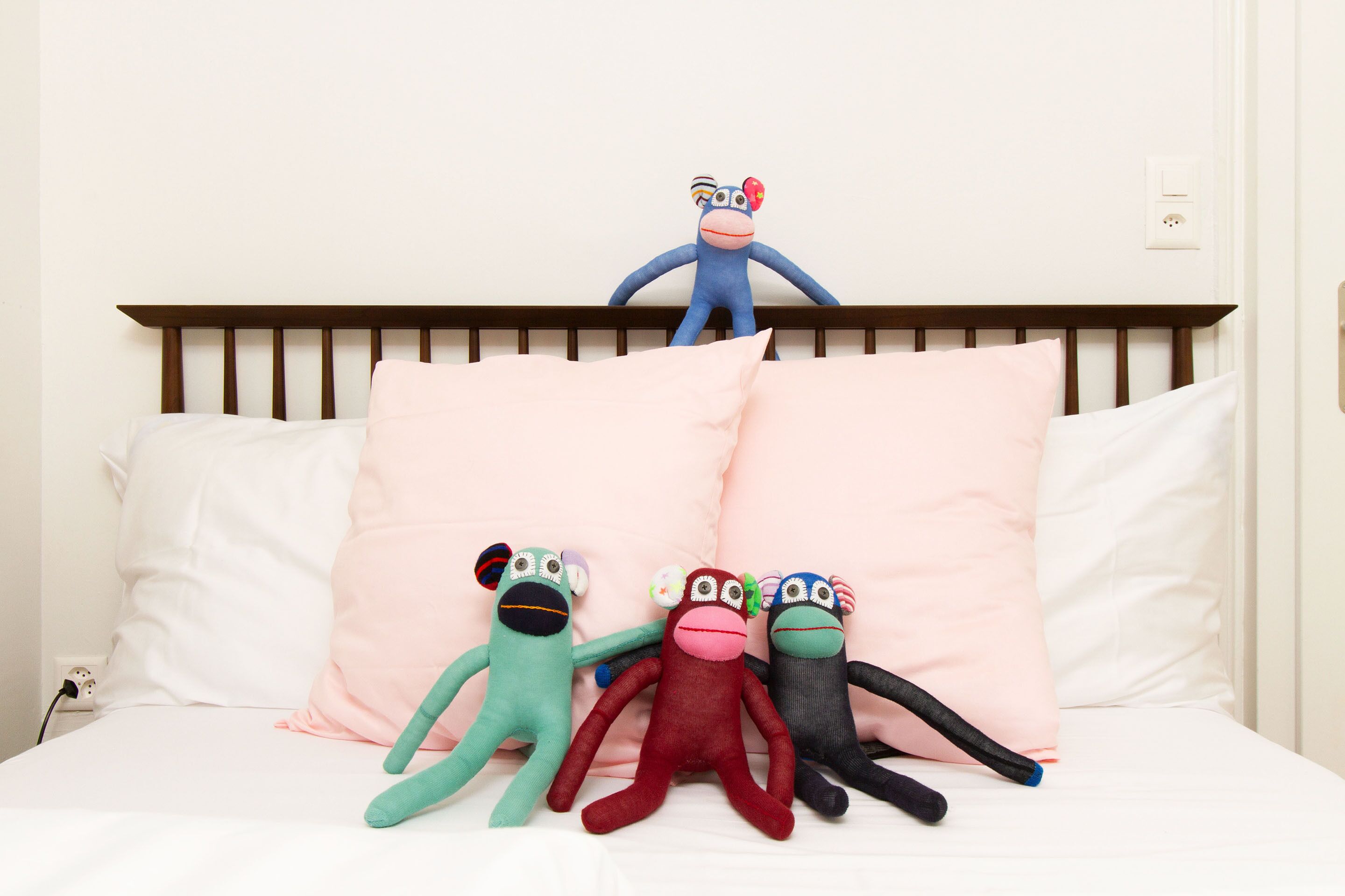 Un lit avec une tête de lit en bois, une literie blanche et quatre peluches.