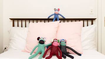 Un lit avec une tête de lit en bois, une literie blanche et quatre peluches.