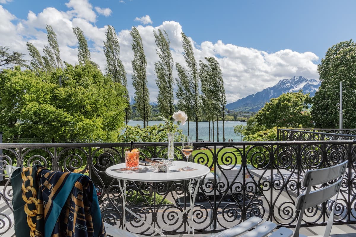 Ein Balkon mit Tisch für Zwei mit Blick auf einen See und Berge.