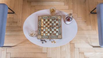 A chessboard on a round table with a bottle and a glass of water beside it.
