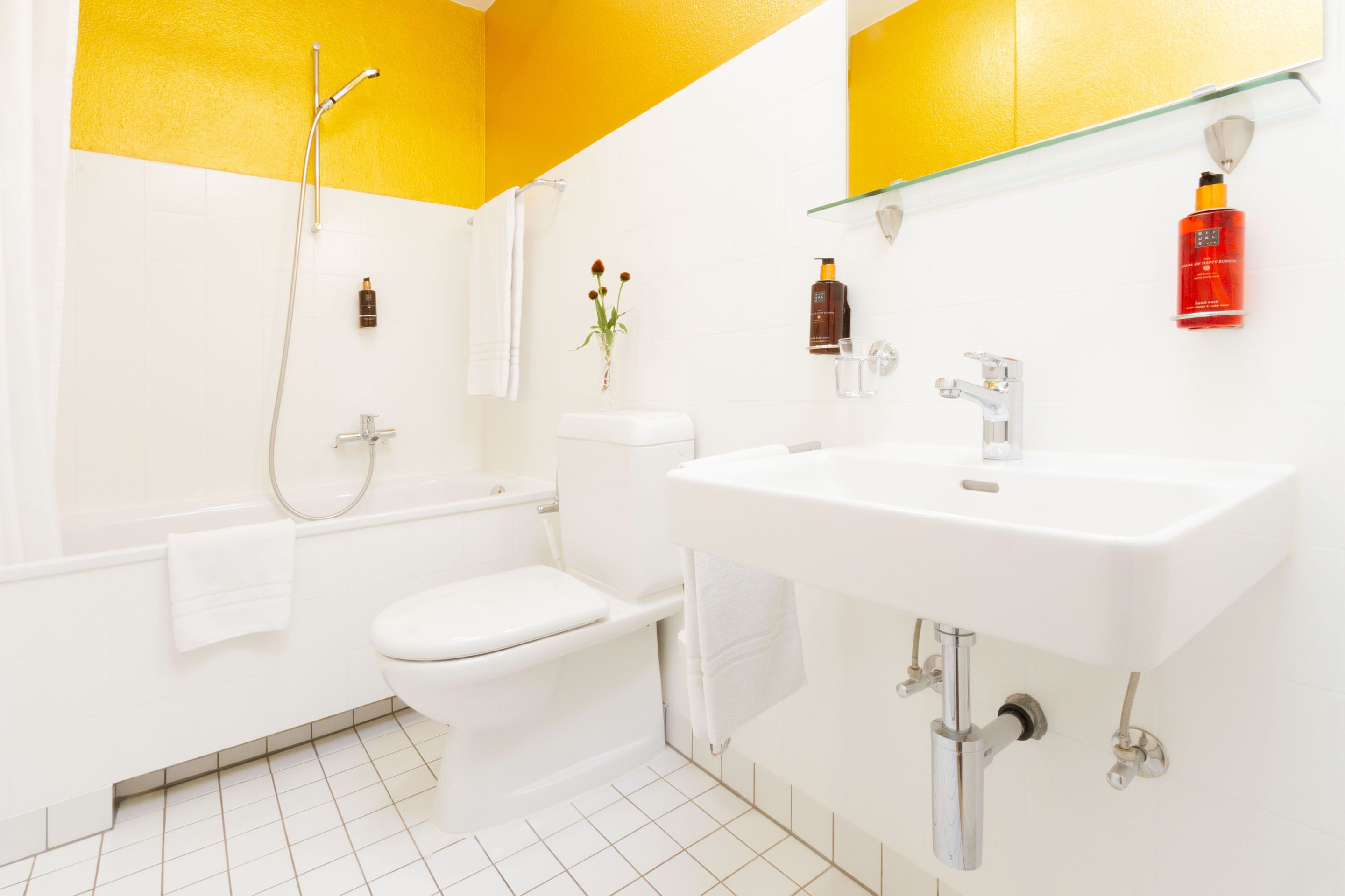 Une salle de bain avec des toilettes blanches, une baignoire, un lavabo et une douche.