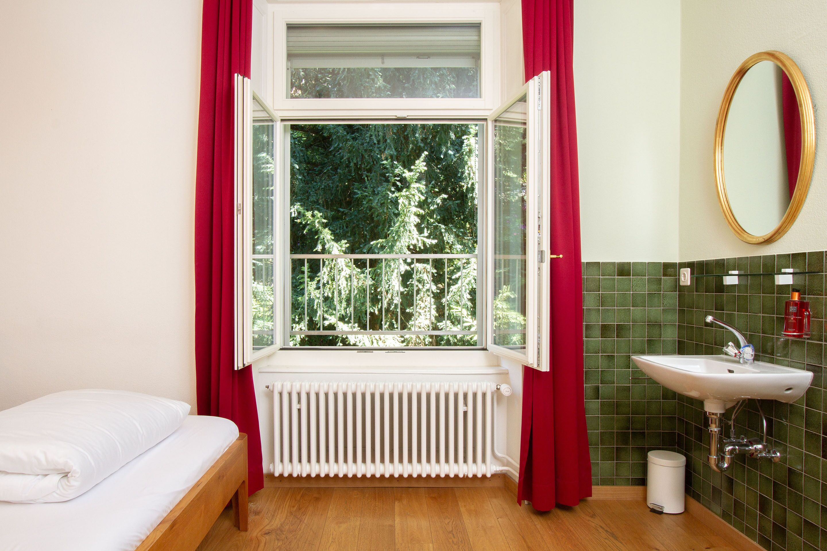 Un baño con ventana, radiador, lavabo y cama.