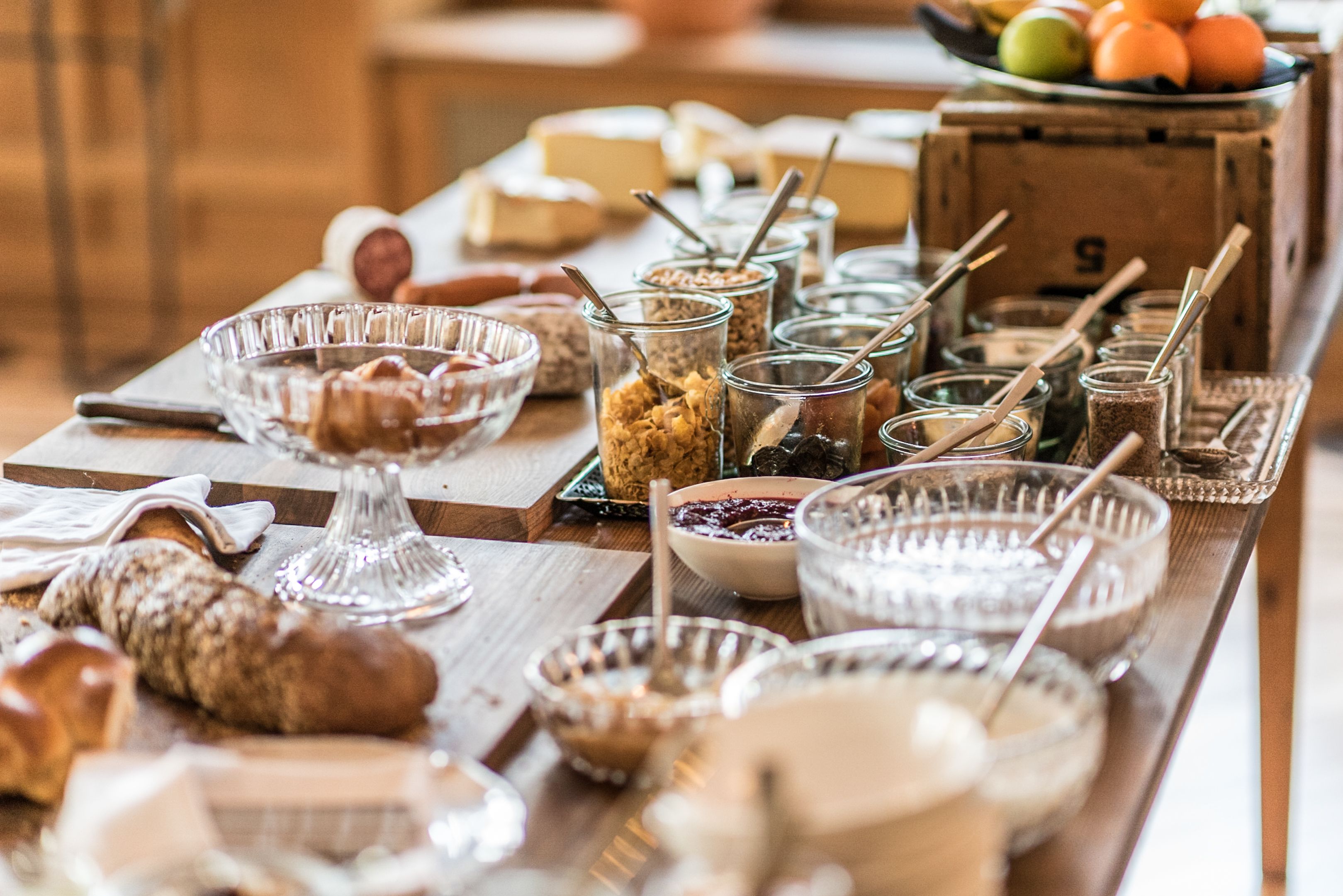 Een buffettafel met diverse etenswaren en bakken, waaronder kommen, potten en een glazen schaal.