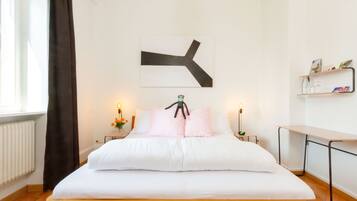 Una cama bien hecha con estructura de madera, un cuadro abstracto en la pared y mesitas de noche con lámparas.