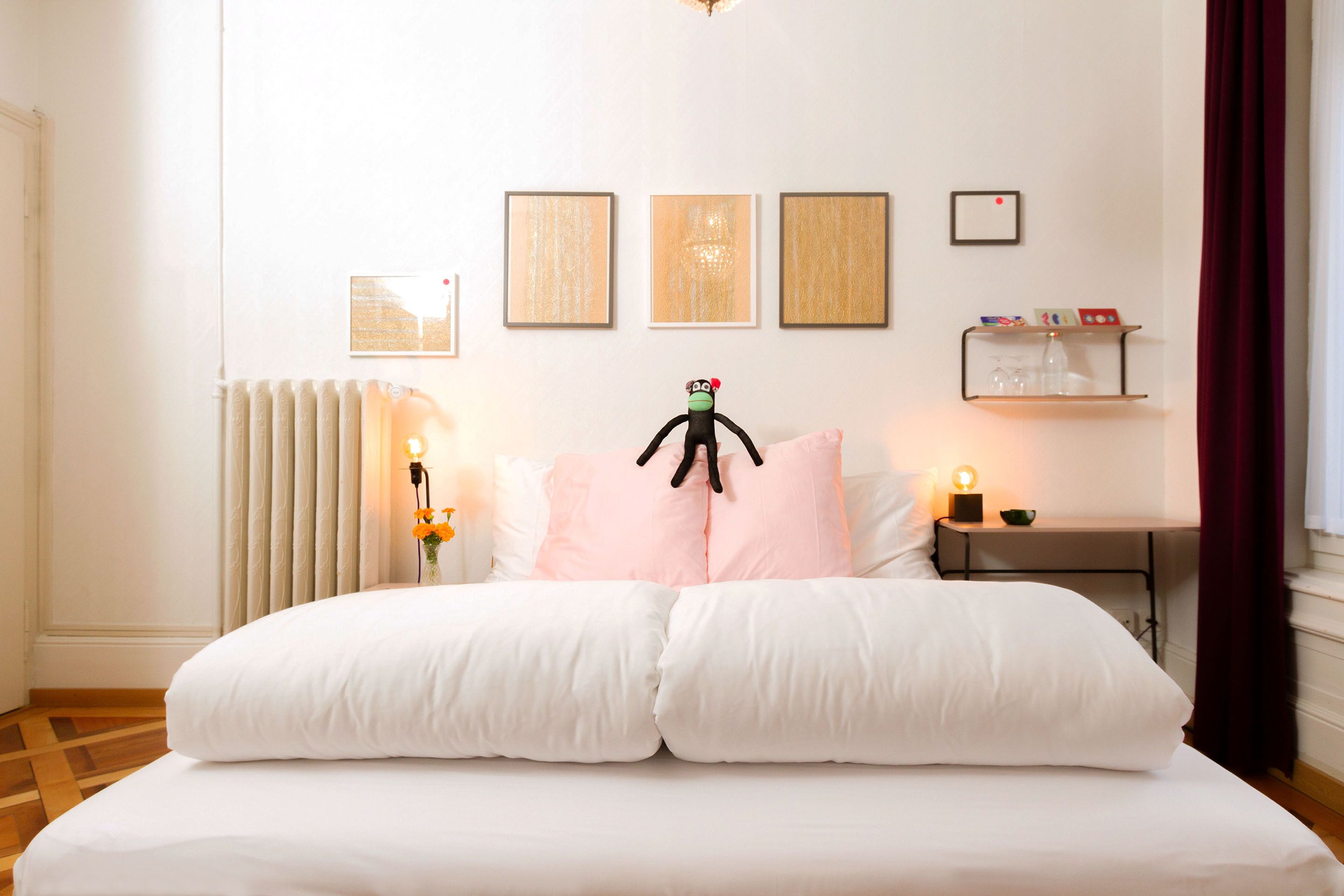 Une chambre avec un grand lit, un radiateur et des œuvres d’art accrochées au mur.
