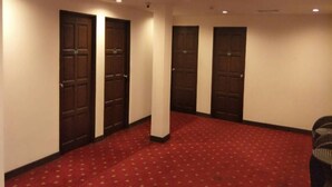 A hallway with four doors, a red carpet, and a ceiling with recessed lighting. - Hotel Mercury (Kuala Lumpur)