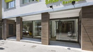 Un edificio moderno con un letrero que dice "SmartRoom Barcelona" y grandes puertas de vidrio.