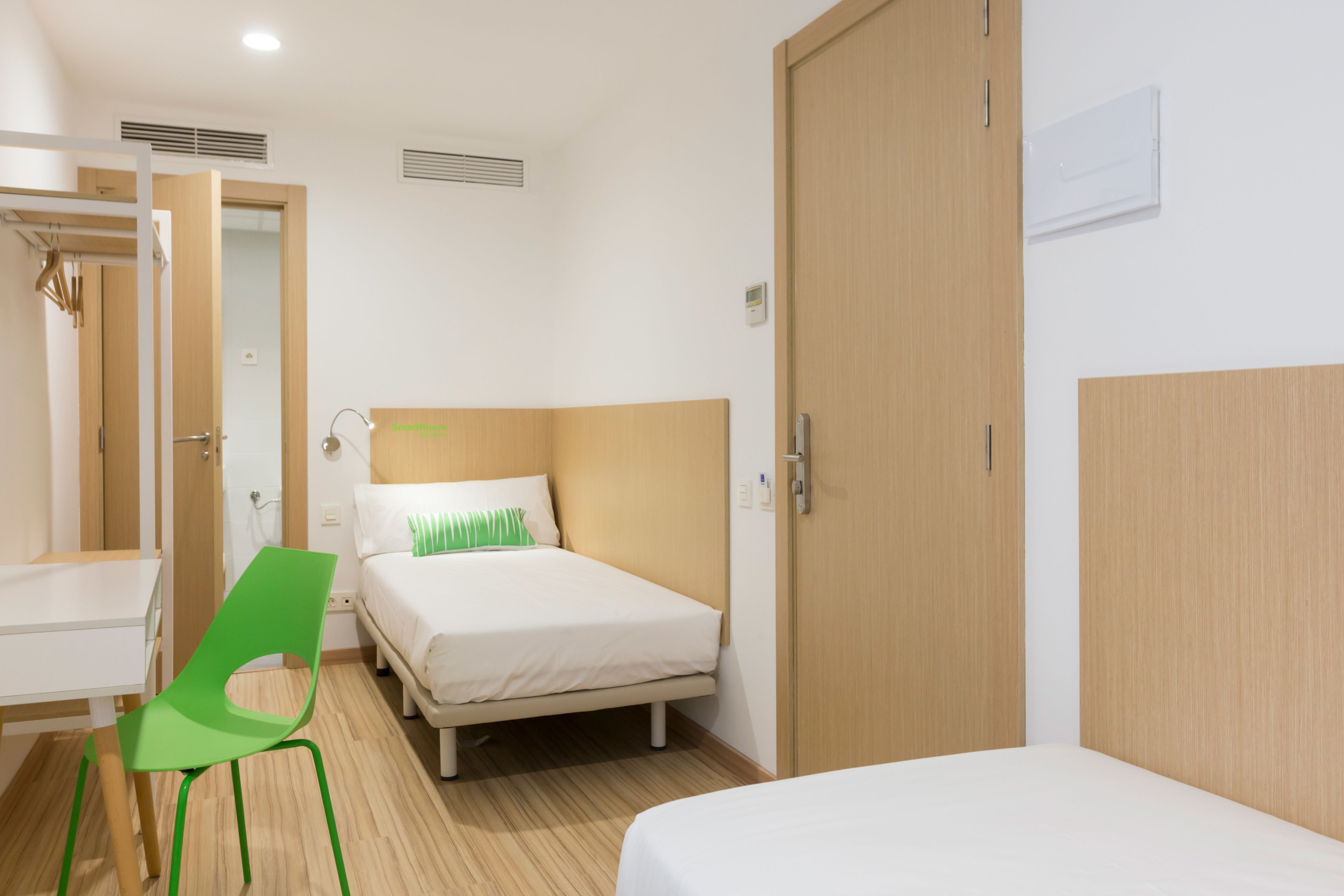 Ein Hotelzimmer mit zwei Betten, einem Schreibtisch, einem Stuhl und einem Kleiderschrank.