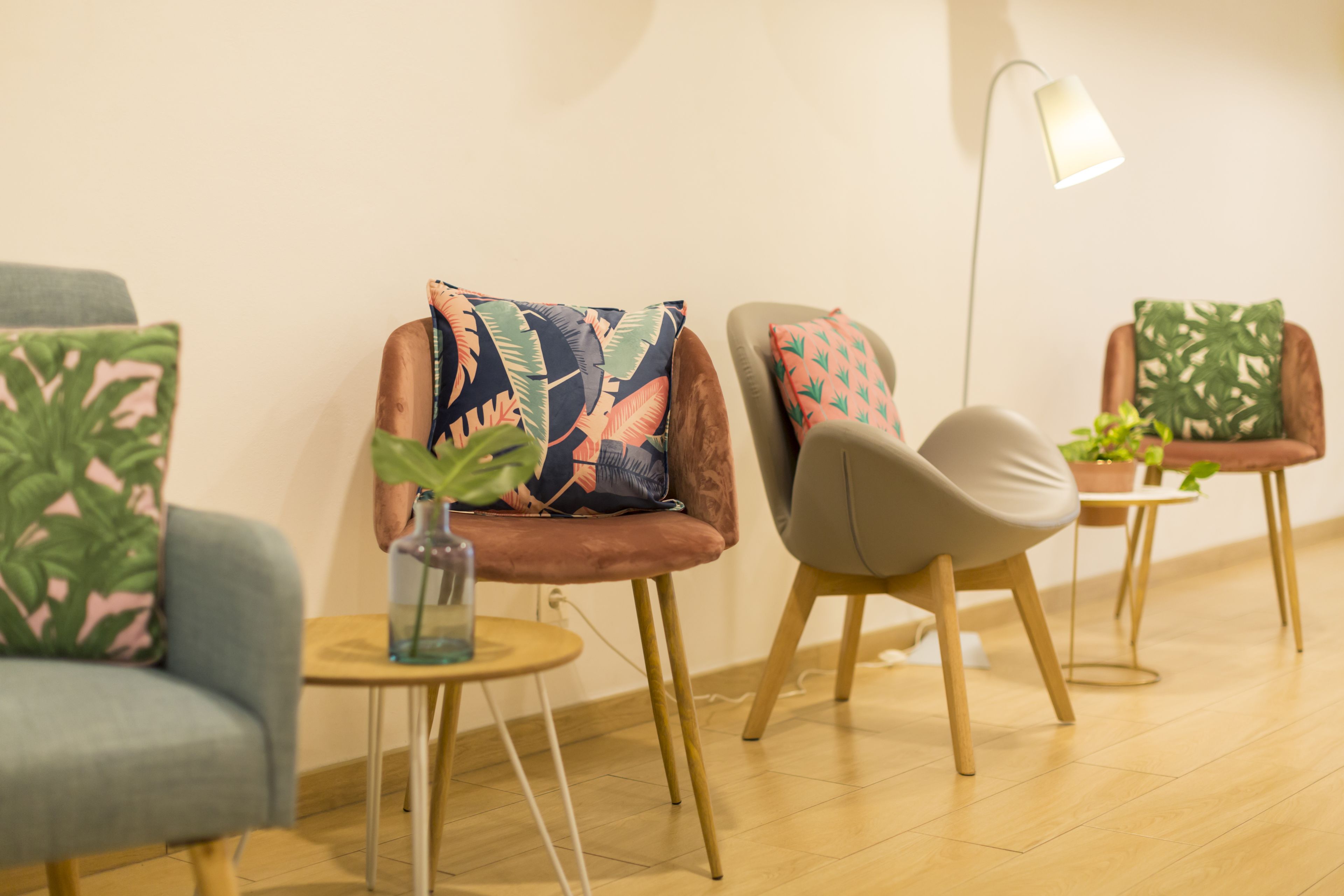 A modern living room with a brown sofa, a grey armchair, and a small round table with a vase.