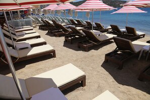 A beachside lounge area with rows of sun loungers and umbrellas, overlooking the sea. - Bitez Otel (Bodrum)