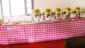 Ein Konferenzraum mit kariertem, pinkfarbenem Tischlauf und einem Fenster, ausgestattet für ein Buffet.