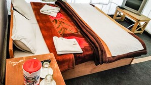 Ein Hotelzimmer mit einem Bett, einem Fernseher auf einem Holzboden und einem Tisch mit einer Flasche und Gläsern.