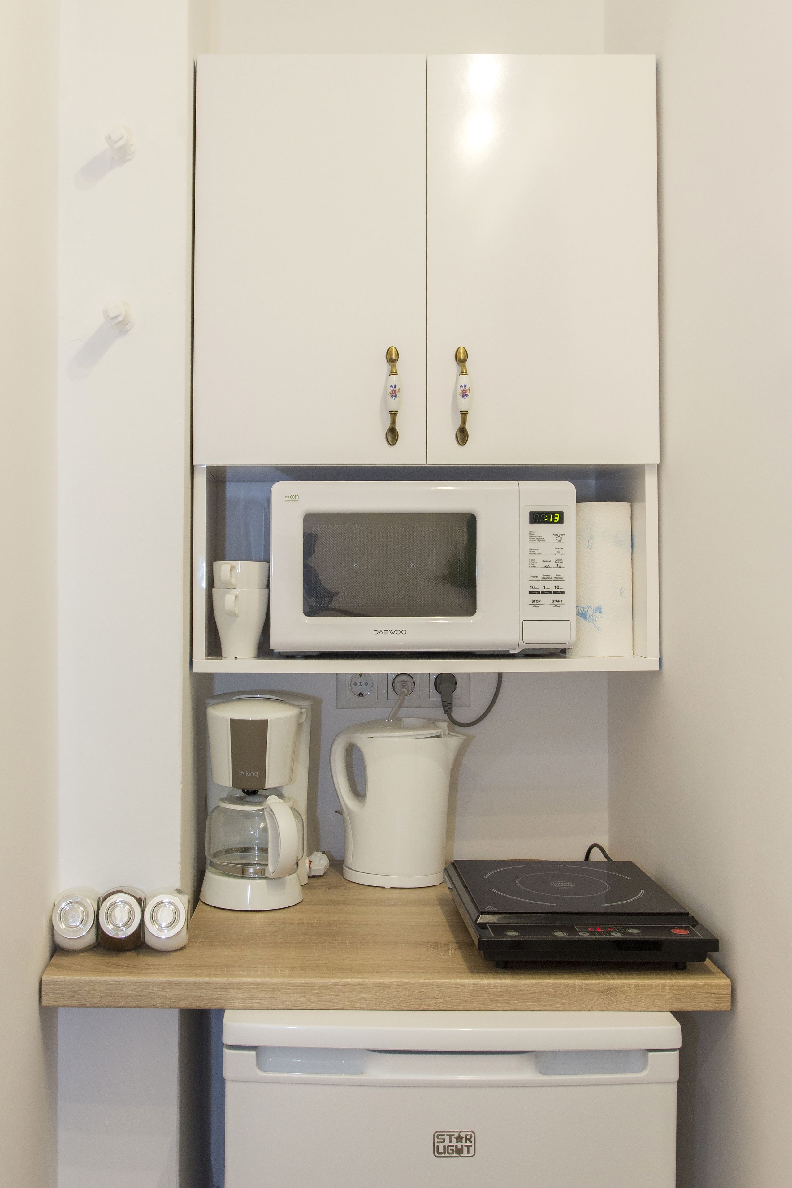 Une petite cuisine équipée d’un four à micro-ondes, d’une machine à café et d’un petit réfrigérateur.