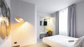 Een moderne hotelkamer met een bed, bureau, stoel en een schilderij aan de muur.