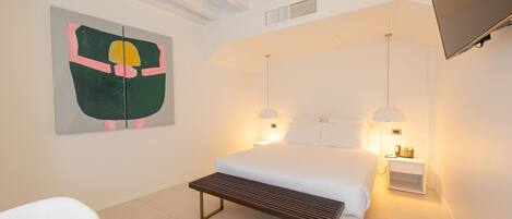 A modern bedroom with a bed, bedside lamps, a bench, a wall-mounted TV, and a painting.