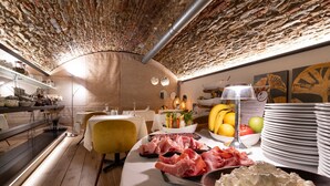 Un restaurante con techo de ladrillo, mesas blancas y diversos platos expuestos.