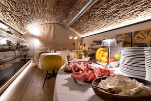 A restaurant with a brick ceiling, white tables, and a variety of food items displayed on the tables. - Le Funi Hotel (Bergamo)