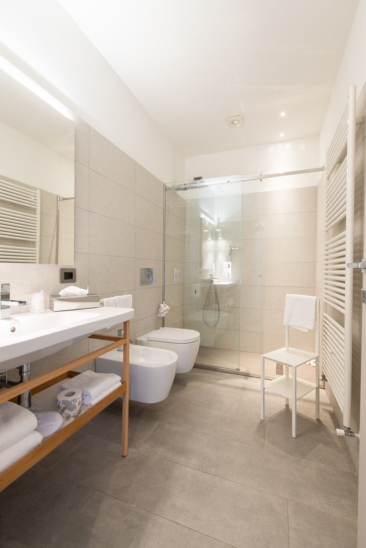 A modern bathroom with a glass-enclosed shower, a white sink, and a toilet.
