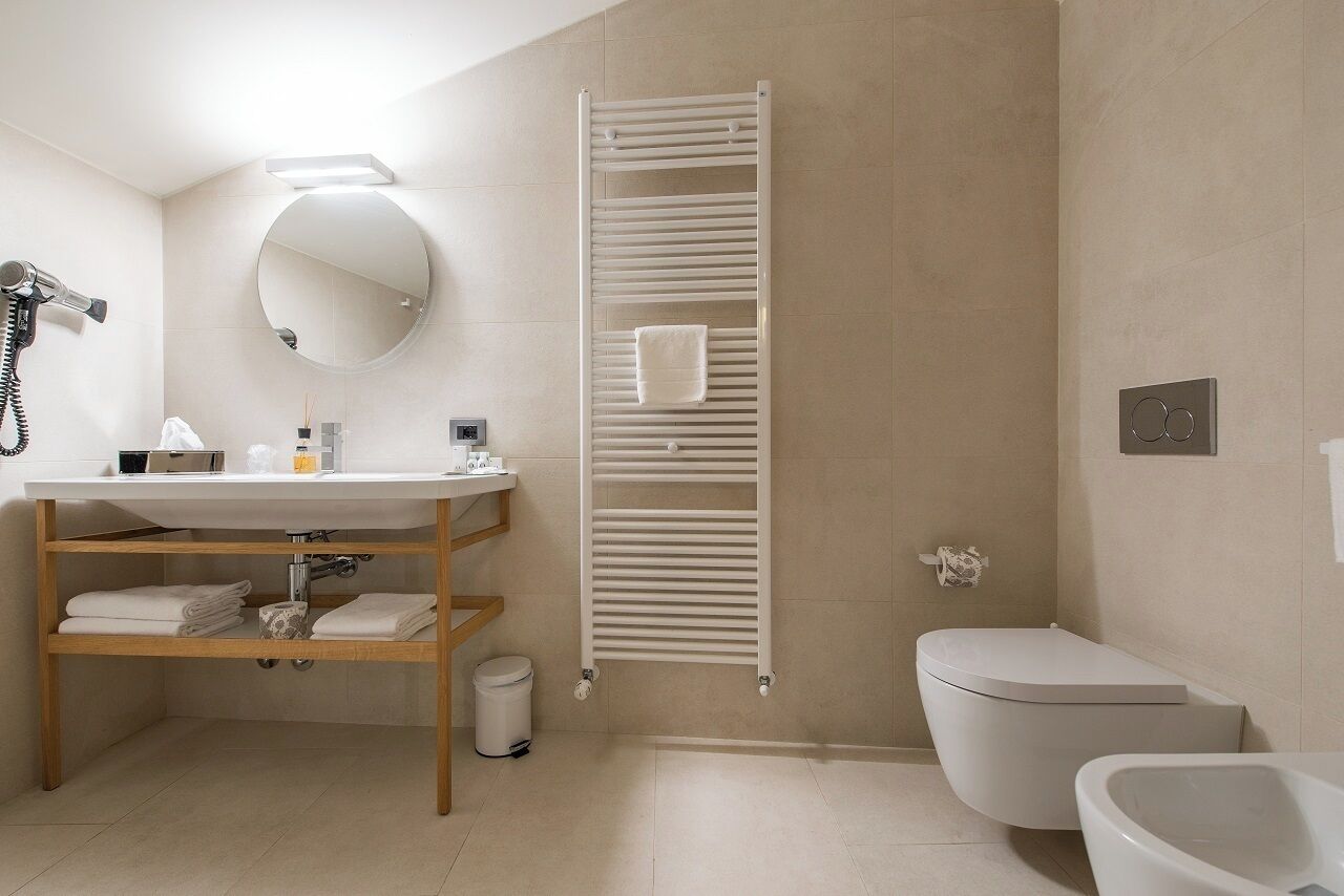 A modern bathroom with a sink, mirror, towel rack, toilet, and a hairdryer.