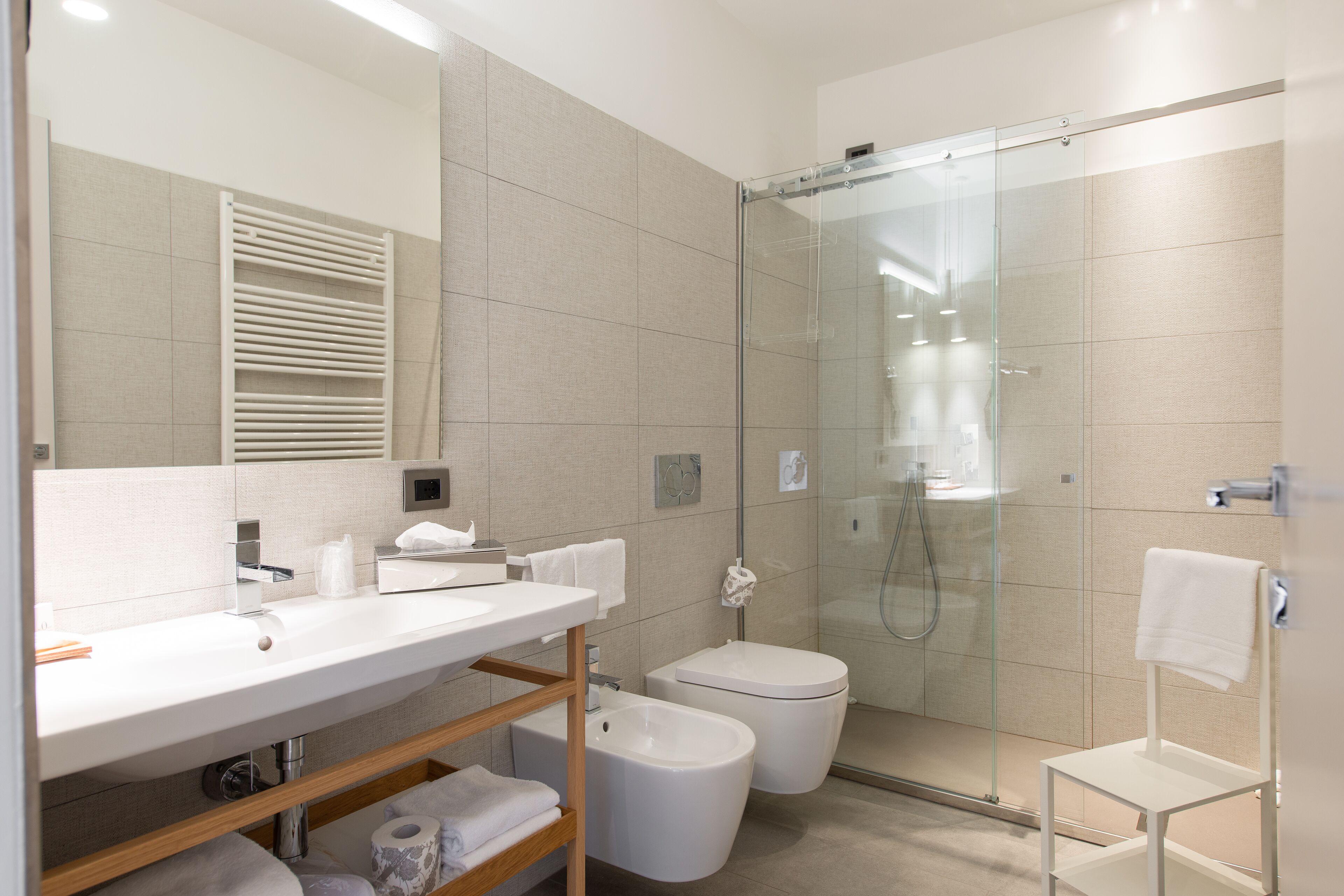 A modern bathroom with a large mirror, a sink, a toilet, and a glass-enclosed shower.