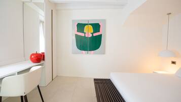 Una habitación de hotel moderna con un escritorio blanco, una cama con cabecero de madera y un cuadro abstracto grande en la pared.