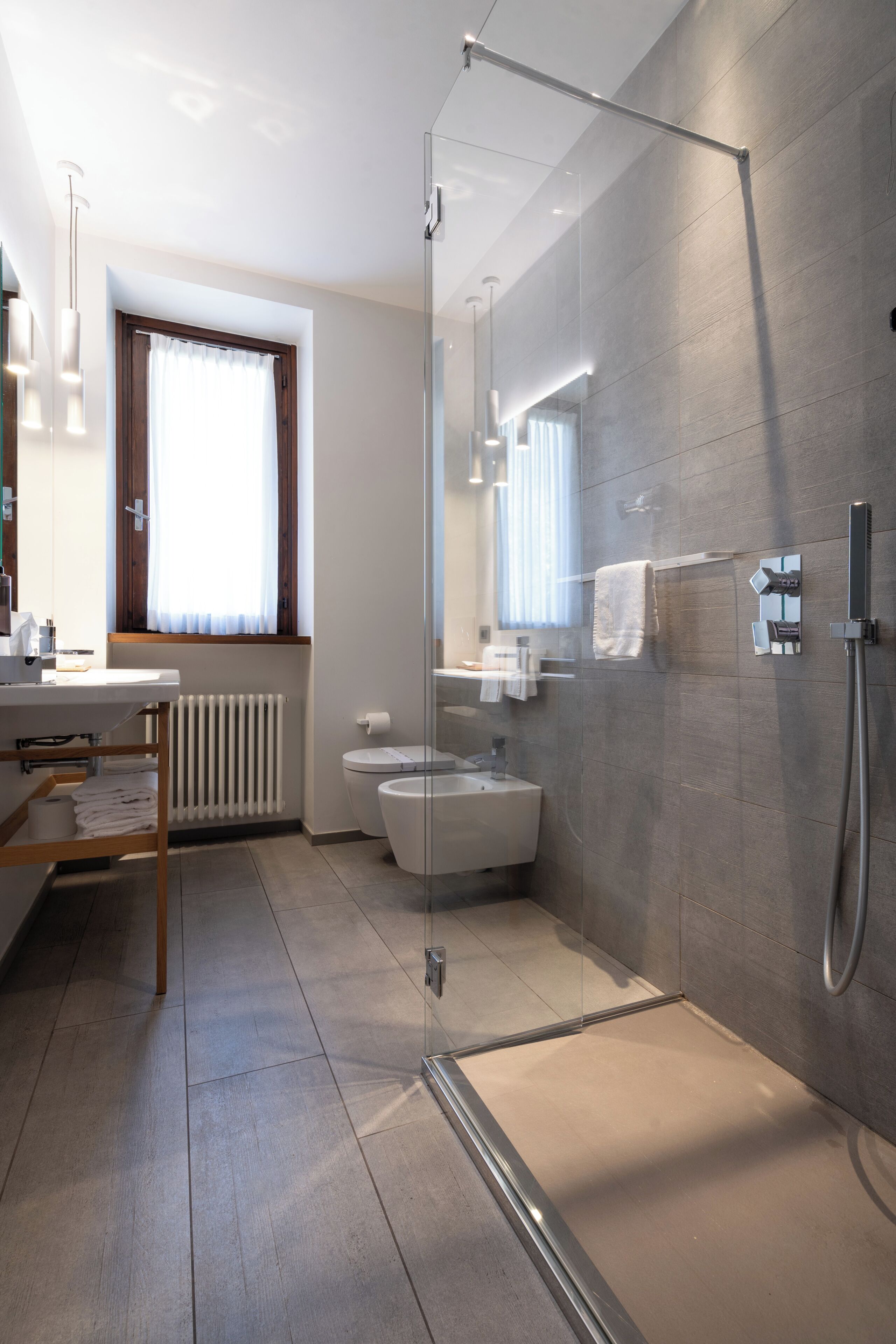 A modern bathroom with a glass shower enclosure, a toilet, and a sink.