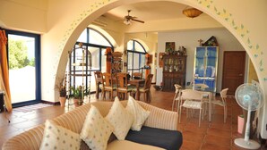 Una sala de estar acogedora con sofá, sillas, una mesa de comedor y un ventilador.