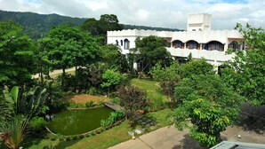 Un edificio blanco con ventanas arqueadas y un estanque en el jardín.