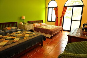 A room with two beds, a small table, a lamp, and a window with curtains. - Tuscany Garden B&B (Guanxi)
