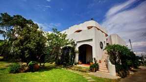 Una casa moderna con un diseño arquitectónico único, que presenta una gran entrada en arco y una escalera que lleva a la puerta principal.