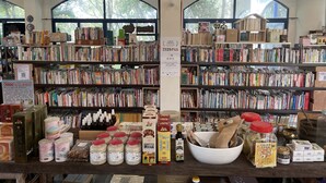 Una librería con múltiples estanterías llenas de libros y diversos productos sobre el mostrador.