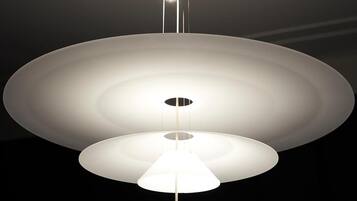 A modern ceiling light fixture with a central circular design and a smaller circular light below it.