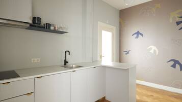 A modern kitchen with white cabinetry, a built-in sink, and a wooden floor.