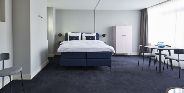 A modern hotel room with a bed, a wardrobe, a desk, and chairs. - Hotel Pistache Den Haag (The Hague)