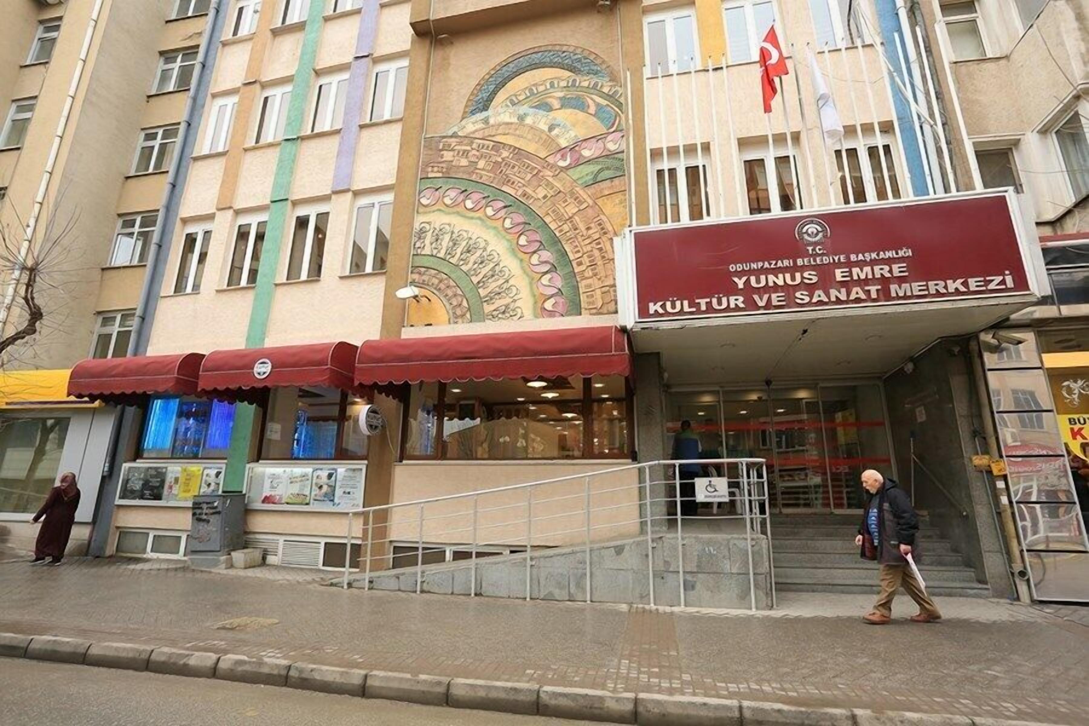 A building with a sign for 'KULTUR VE SANAT MERKEZİ' and a colorful mural on the facade.