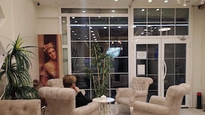 A lobby with tufted armchairs, a round table, and a large poster. - Peri 26 Otel (Eskisehir)