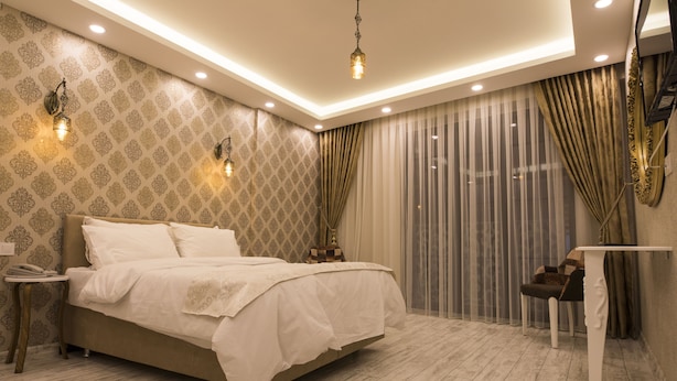 A modern bedroom with a large bed, bedside tables, and a small table. - Peri 26 Otel (Eskisehir)