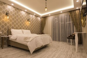 A modern bedroom with a large bed, bedside tables, and a small table. - Peri 26 Otel (Eskisehir)