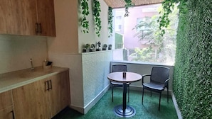 A compact kitchen with wooden cabinets, a round table with two chairs, and a green artificial turf floor. - Peri 26 Otel (Eskisehir)