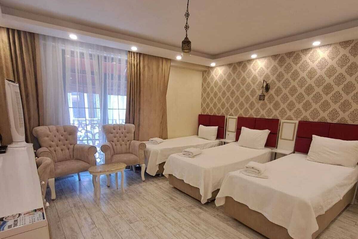 A hotel room with two beds, a desk, a chair, and a large window with curtains.
