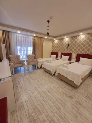 Habitación de hotel con dos camas, un escritorio, una silla y un ventanal con cortinas.